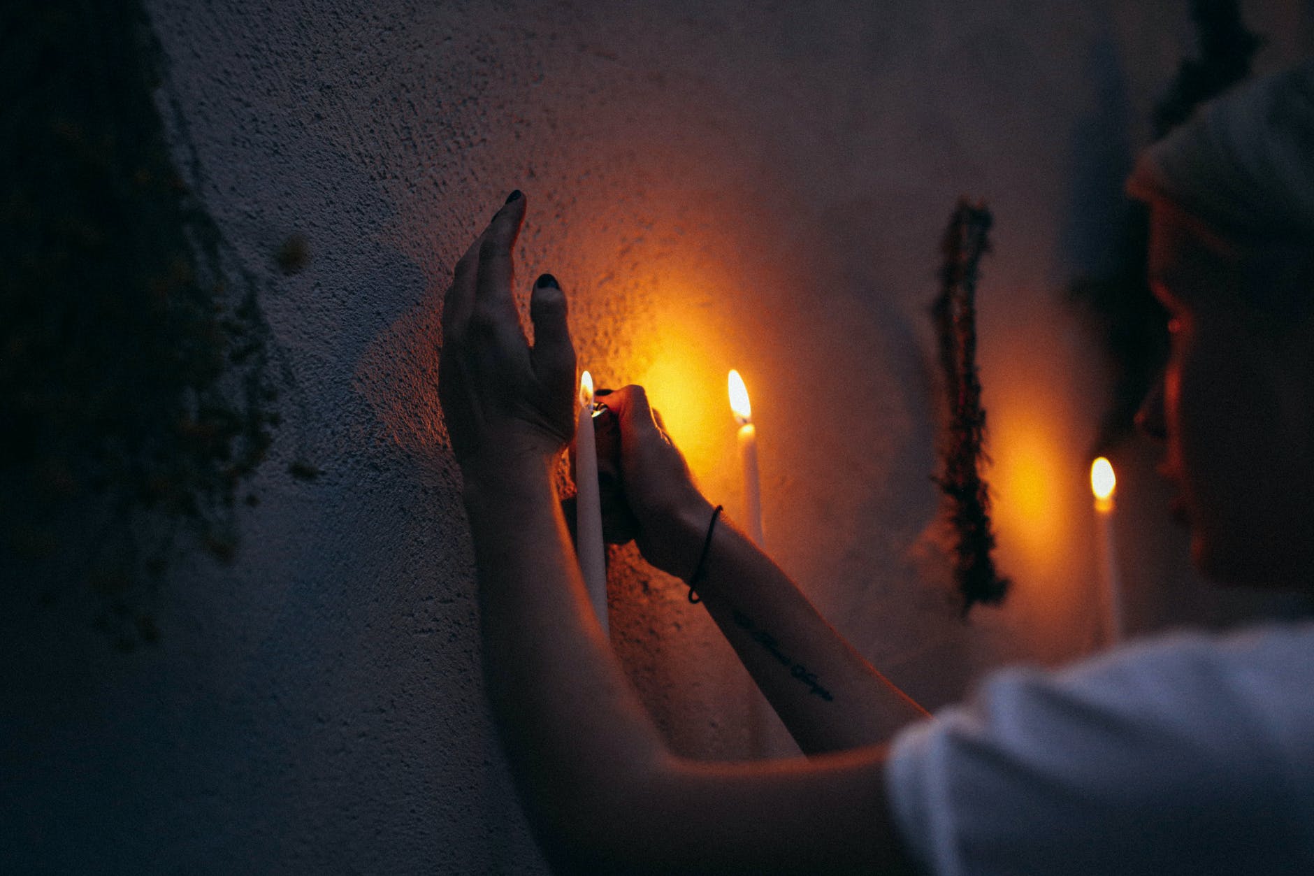 crop woman lighting candle in dark room